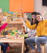 Teacher with preschool students having fun while finger painting at class Teacher with preschool students having fun while finger painting at class