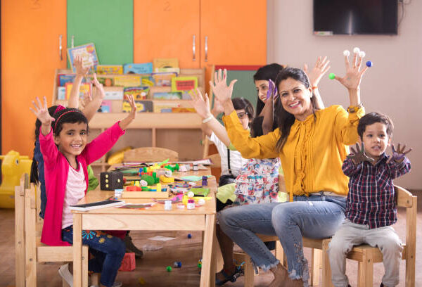 Teacher with preschool students having fun while finger painting at class