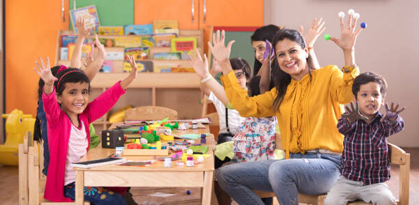 Teacher with preschool students having fun while finger painting at class