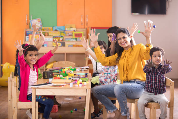 Teacher with preschool students having fun while finger painting at class Teacher with preschool students having fun while finger painting at class