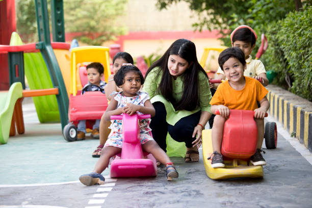 Female teacher with preschool children riding toy rocking horse Female teacher with preschool children riding toy rocking horse
