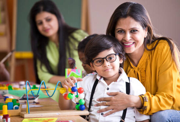 Happy teacher embracing preschool student